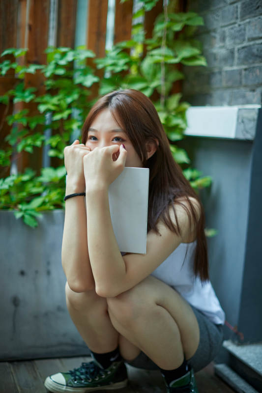 院子里坐在长椅上阅读书籍的亚洲长发少女图片