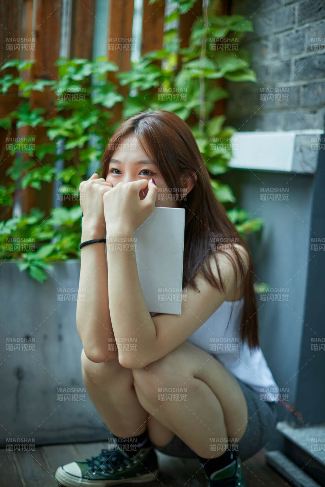 院子里坐在长椅上阅读书籍的亚洲长发少女图片