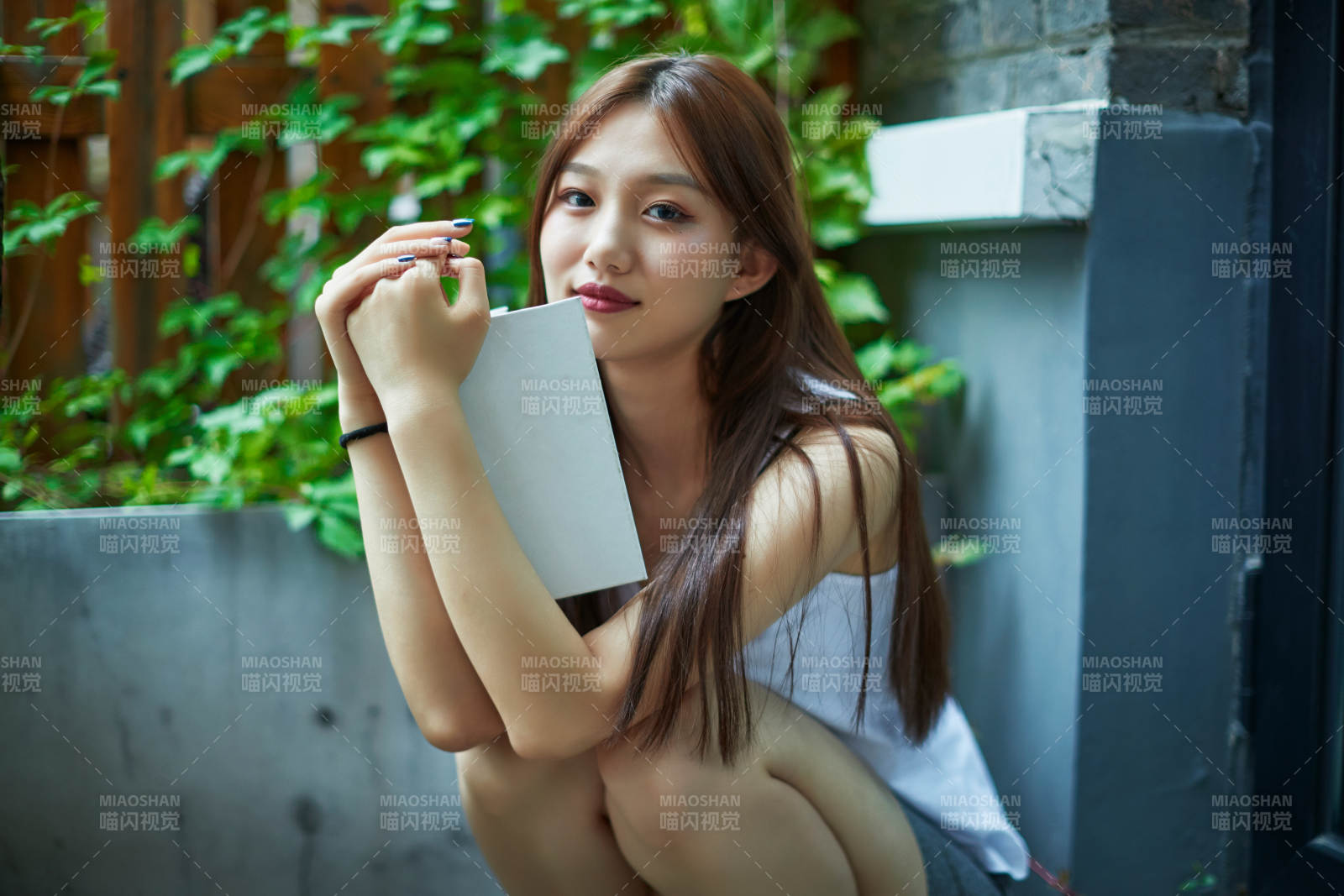 院子里坐在长椅上阅读书籍的亚洲长发少女图片