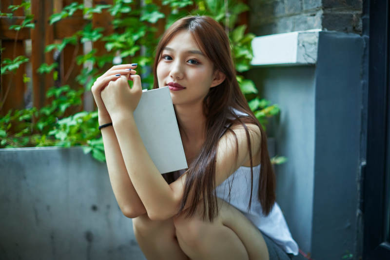 院子里坐在长椅上阅读书籍的亚洲长发少女图片