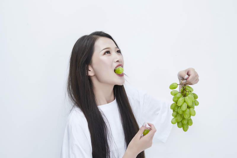 吃葡萄的穿白色长T血衫的长发可爱少女人像图片