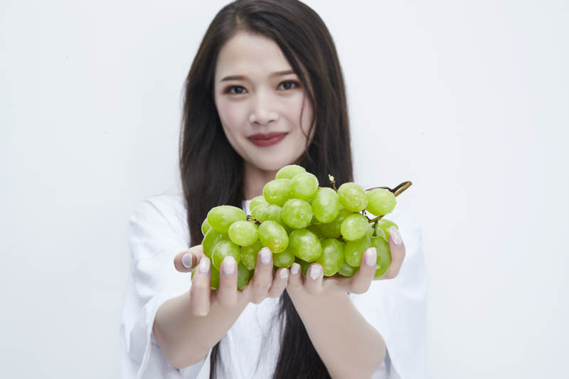 吃葡萄的穿白色长T血衫的长发可爱少女人像图片