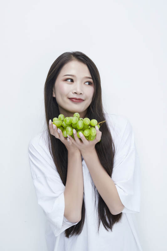 吃葡萄的穿白色长T血衫的长发可爱少女人像图片