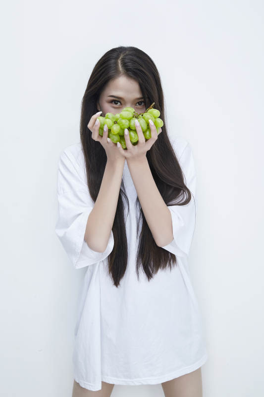 吃葡萄的穿白色长T血衫的长发可爱少女人像图片
