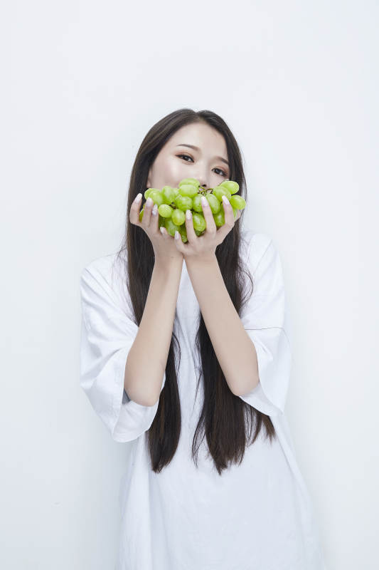吃葡萄的穿白色长T血衫的长发可爱少女人像图片