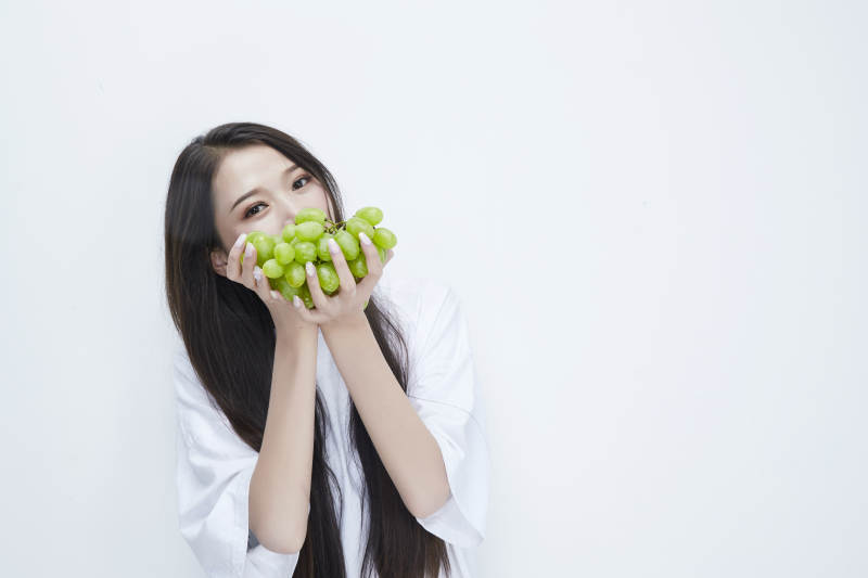 吃葡萄的穿白色长T血衫的长发可爱少女人像图片