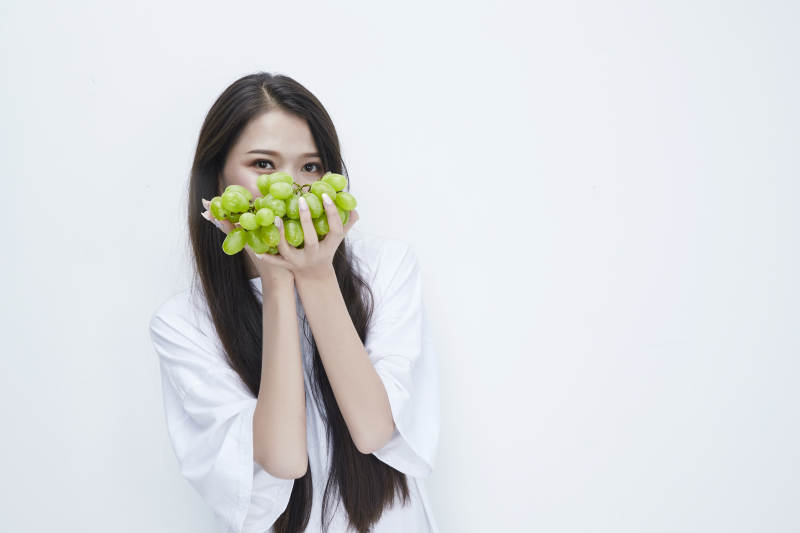 吃葡萄的穿白色长T血衫的长发可爱少女人像图片