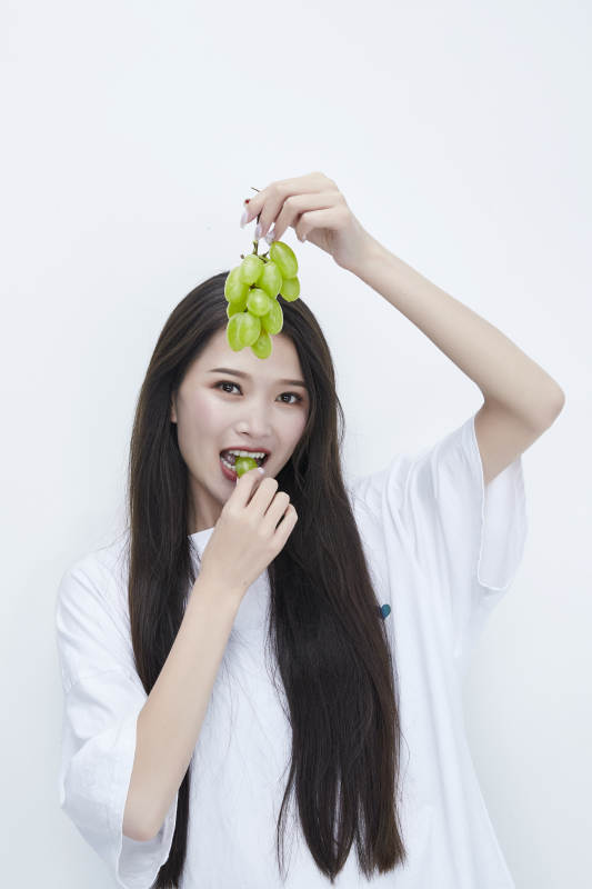 吃葡萄的穿白色长T血衫的长发可爱少女人像图片