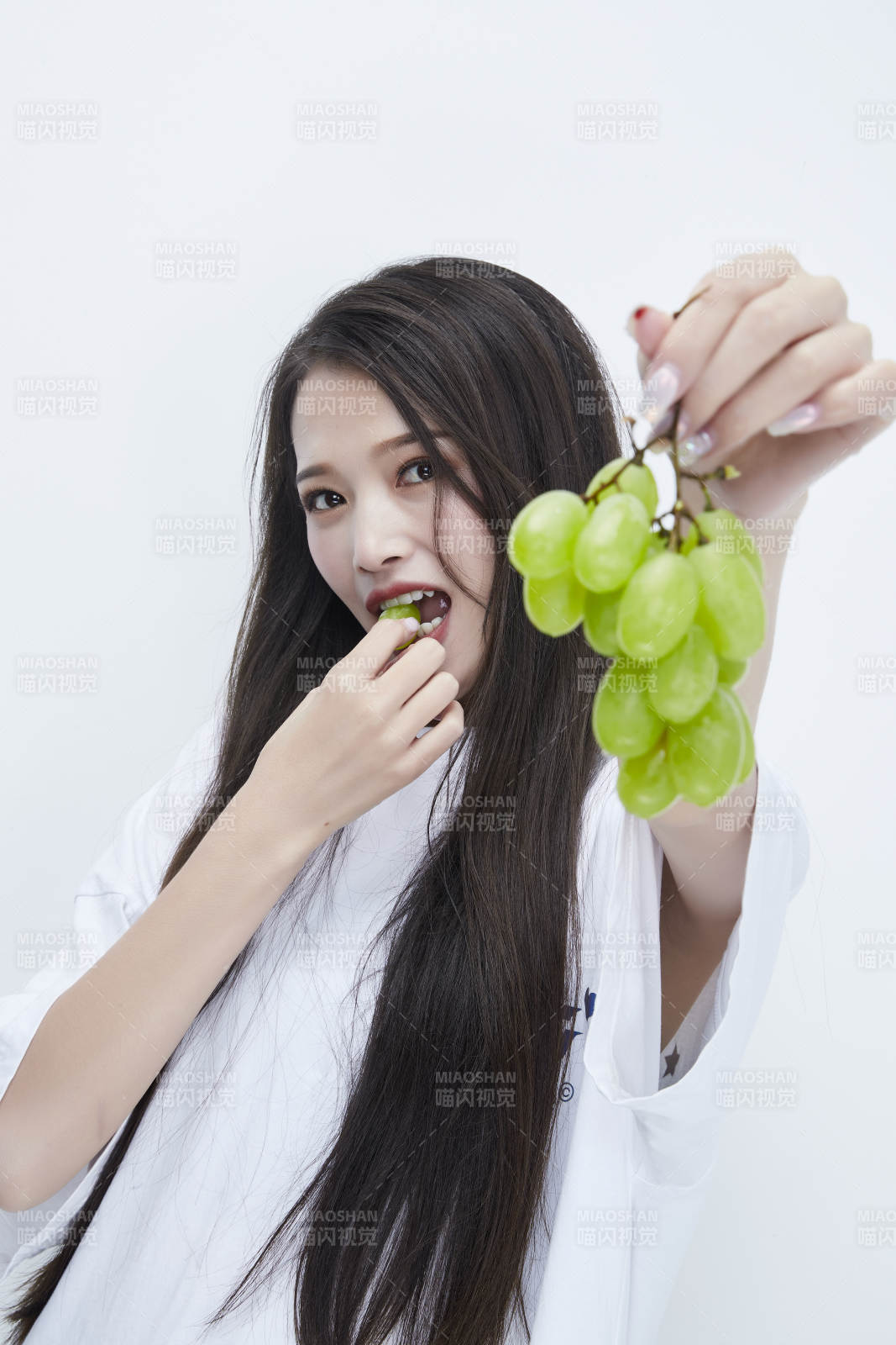 吃葡萄的穿白色长T血衫的长发可爱少女人像图片