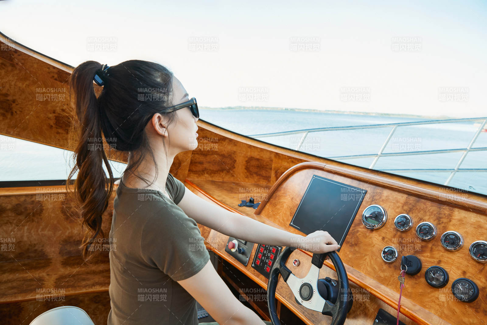 在海上戴着墨镜驾驶游艇的亚洲少女图片