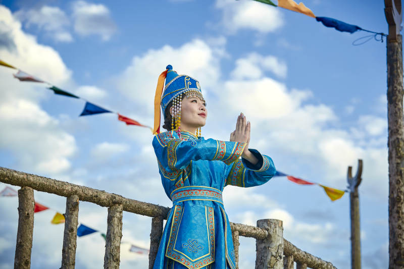 草原上敖包前身穿豪华蒙古族服饰的蒙族少女图片