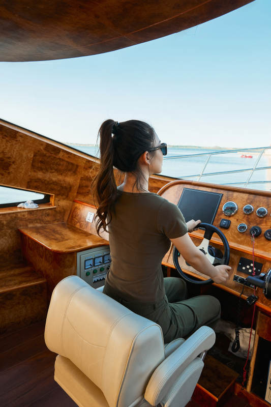 在海上戴着墨镜驾驶游艇的亚洲少女图片