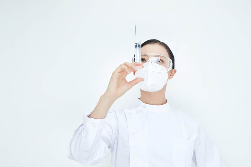 穿护士服戴口罩手执针筒的年轻女护士图片