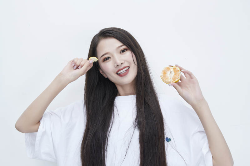 拿着拨开的橙子穿白色长T血的可爱少女人像图片