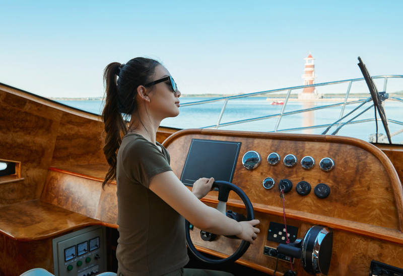 在海上戴着墨镜驾驶游艇的亚洲少女图片