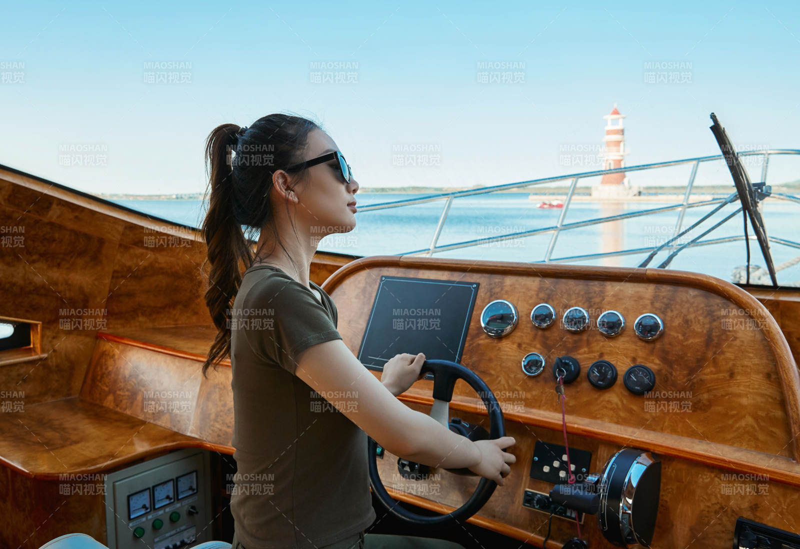 在海上戴着墨镜驾驶游艇的亚洲少女图片