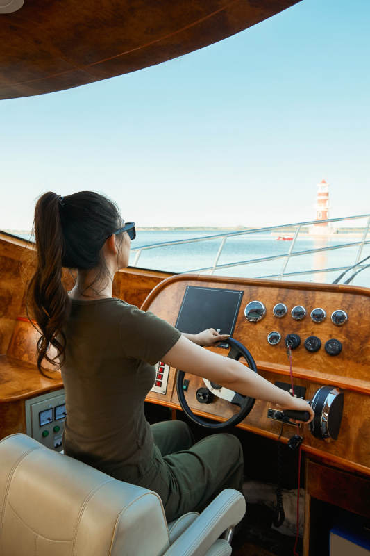 在海上戴着墨镜驾驶游艇的亚洲少女图片