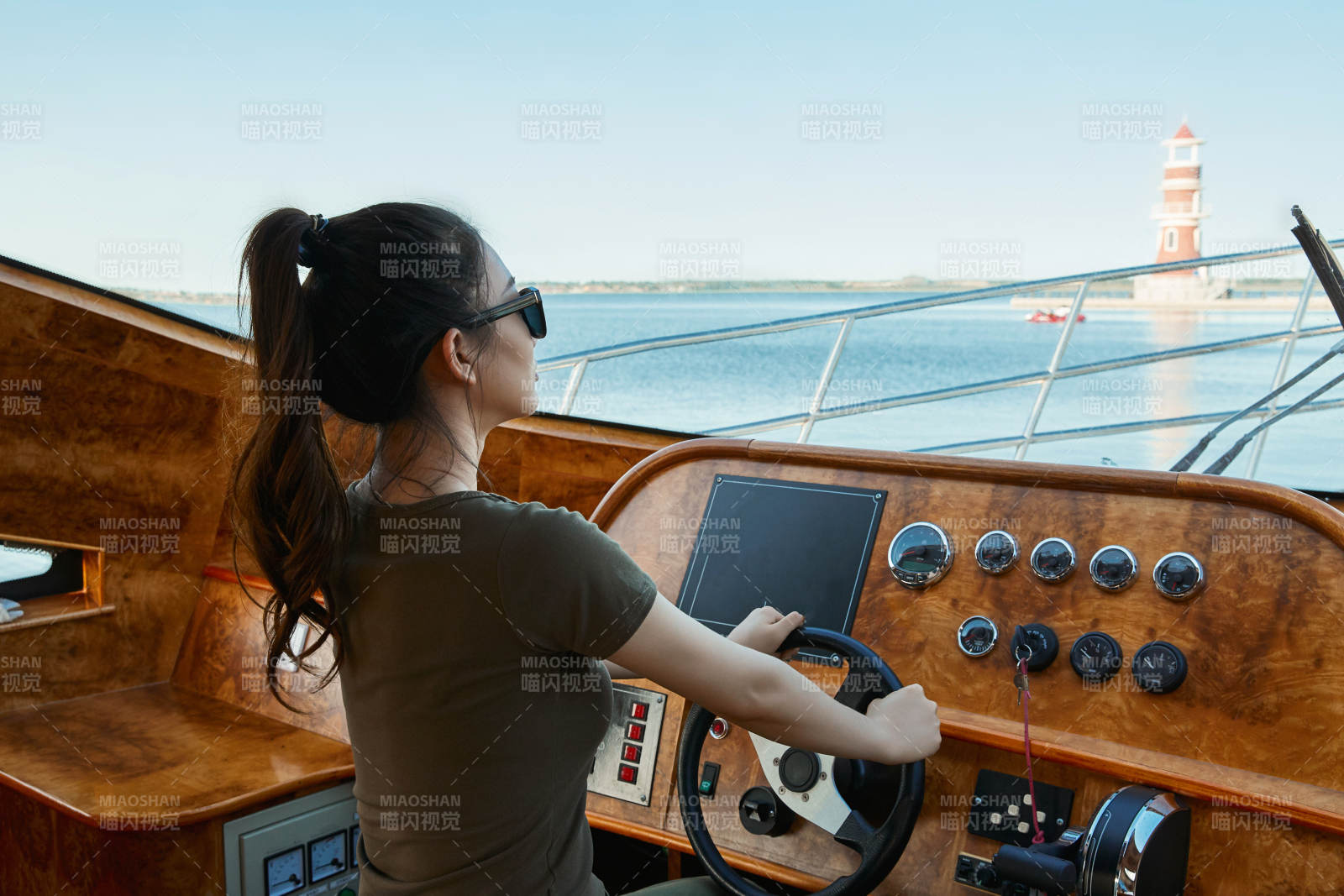 在海上戴着墨镜驾驶游艇的亚洲少女图片