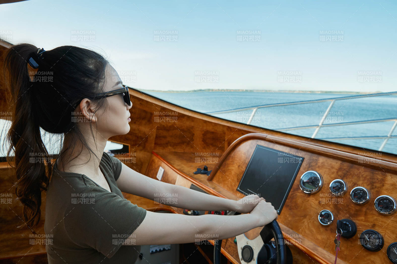 在海上戴着墨镜驾驶游艇的亚洲少女图片