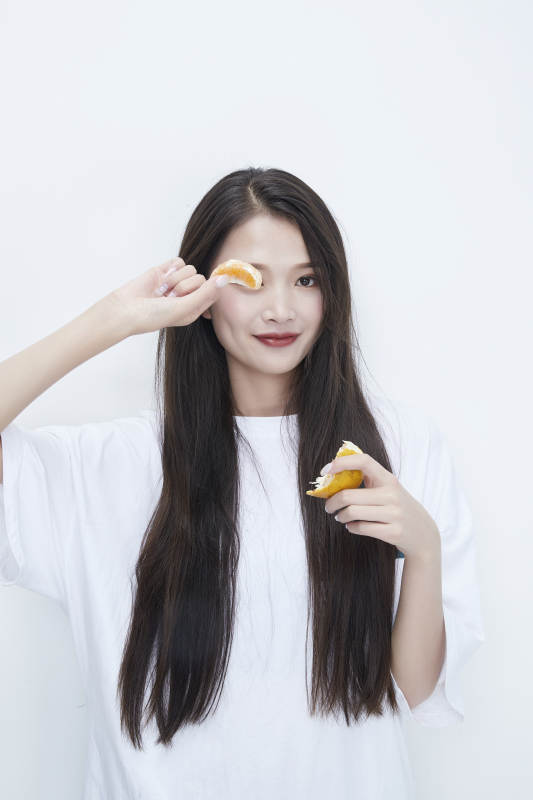 拿着拨开的橙子穿白色长T血的可爱少女人像图片
