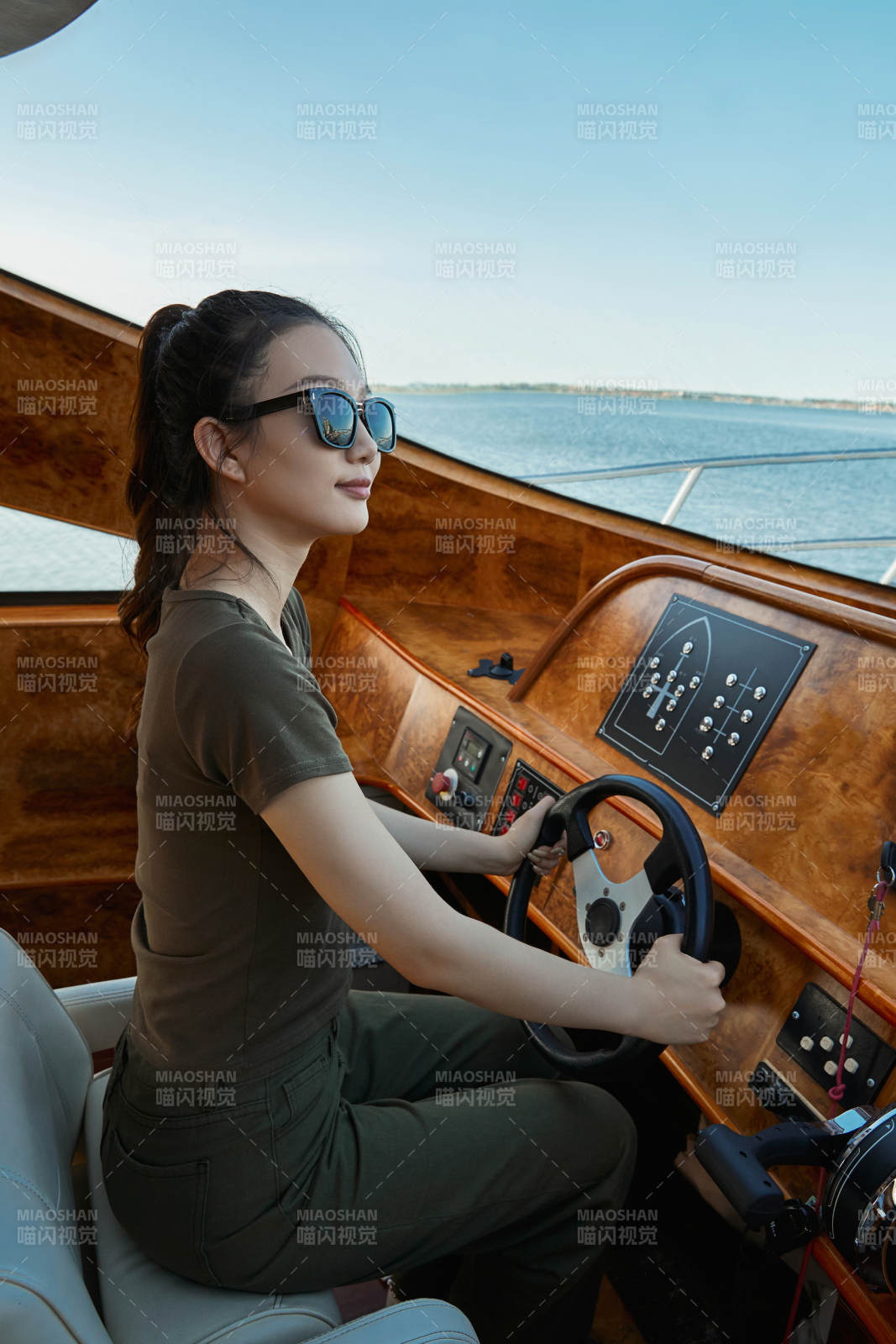 在海上戴着墨镜驾驶游艇的亚洲少女图片