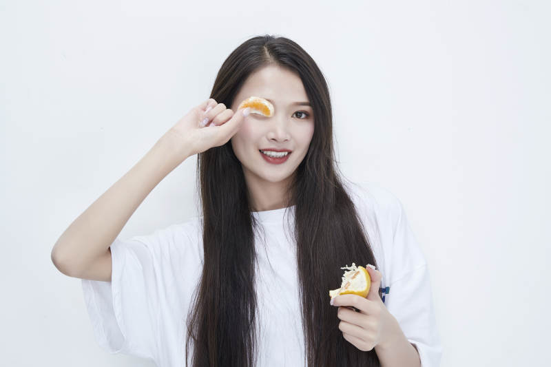 拿着拨开的橙子穿白色长T血的可爱少女人像图片