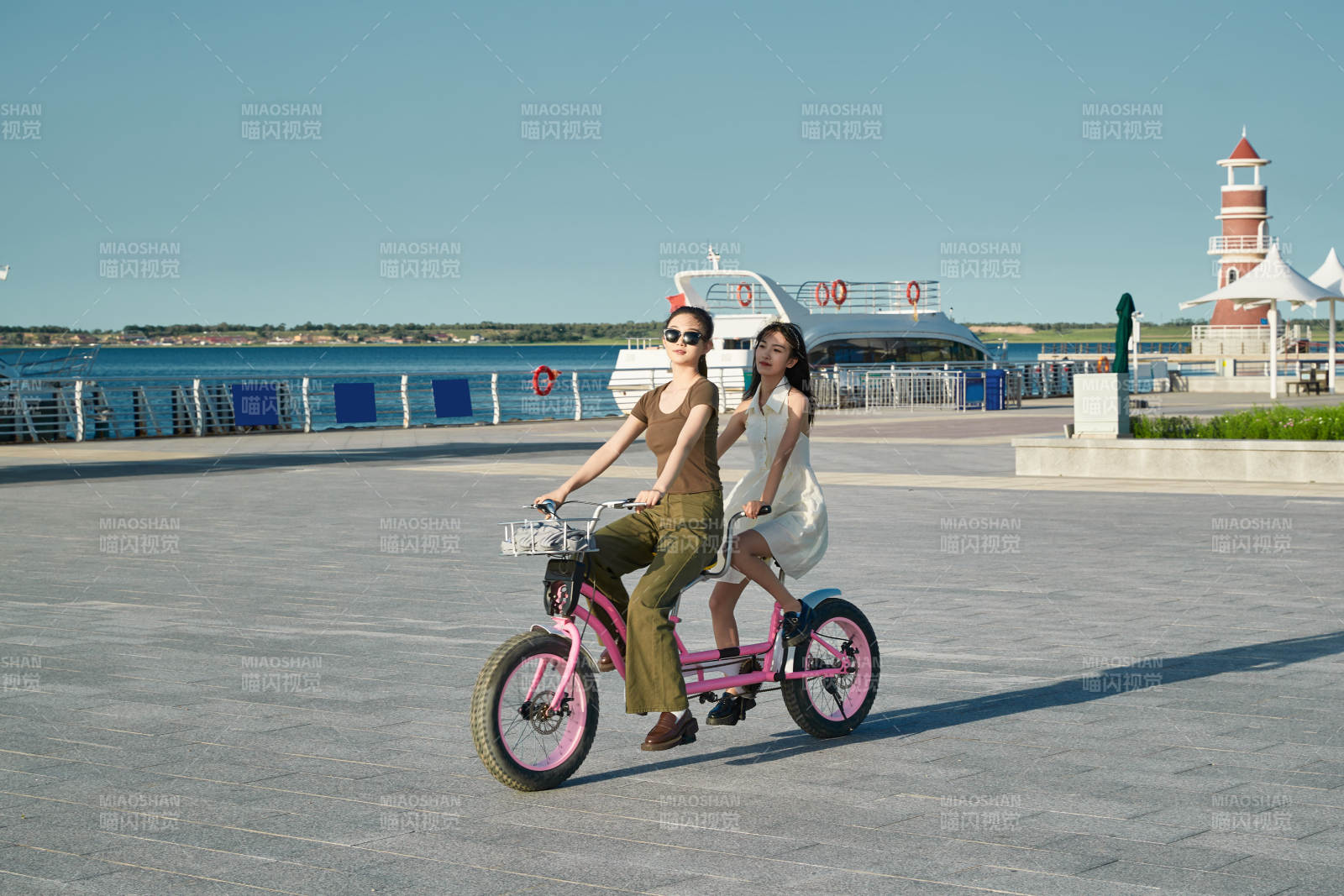 夕阳下湖边码头骑双人脚踏车的闺蜜少女图片