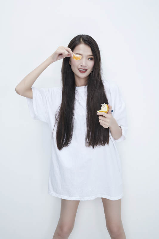 拿着拨开的橙子穿白色长T血的可爱少女人像图片