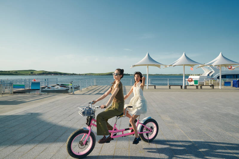 夕阳下湖边码头骑双人脚踏车的闺蜜少女图片