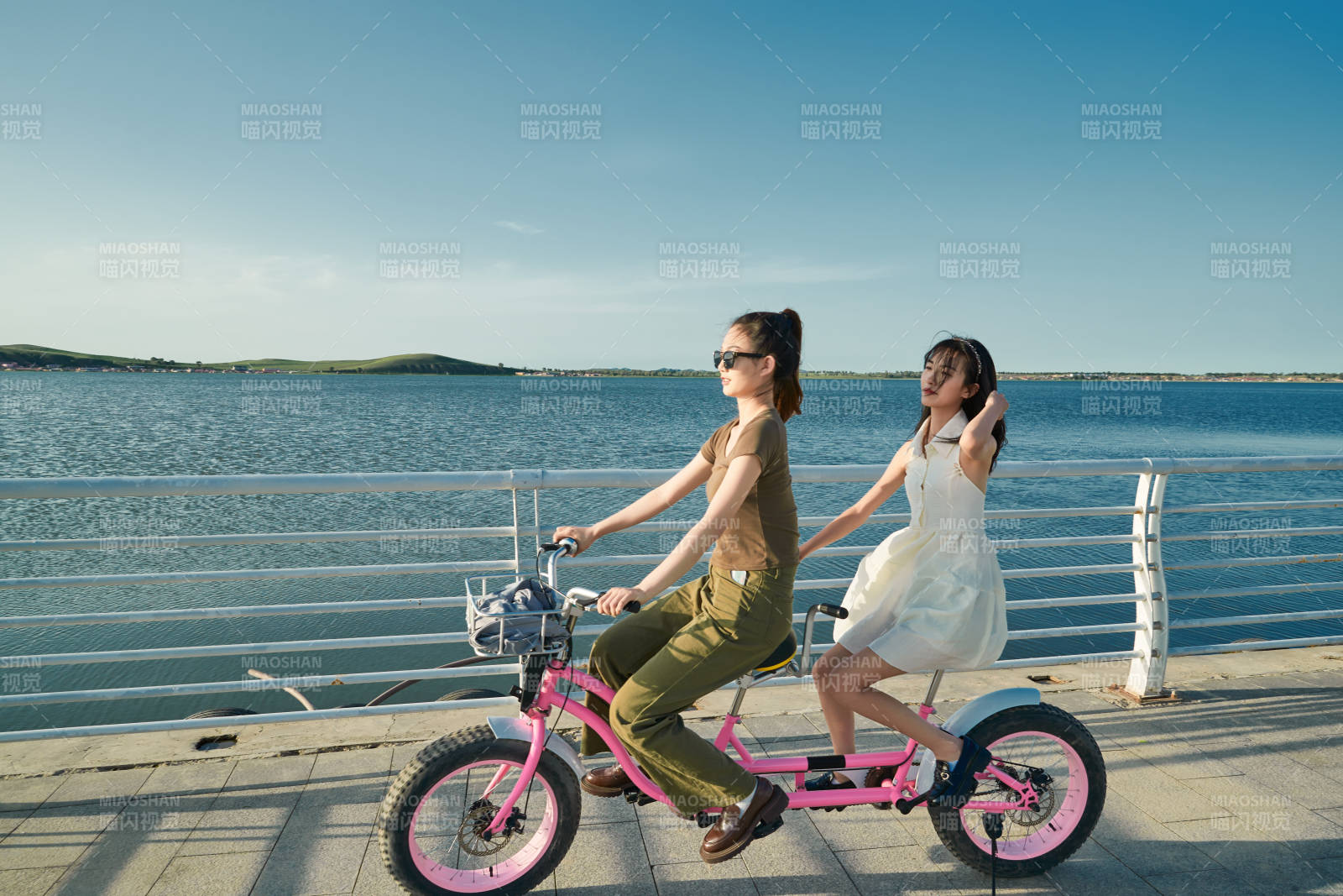 夕阳下湖边码头骑双人脚踏车的闺蜜少女图片