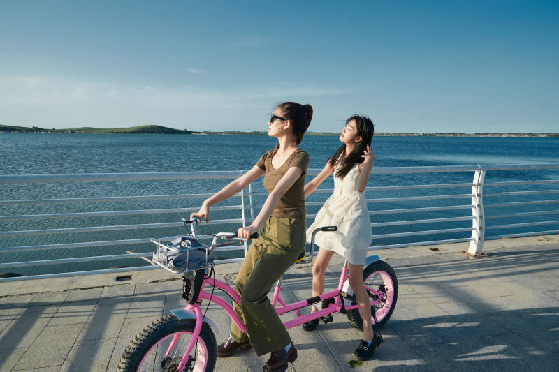夕阳下湖边码头骑双人脚踏车的闺蜜少女图片