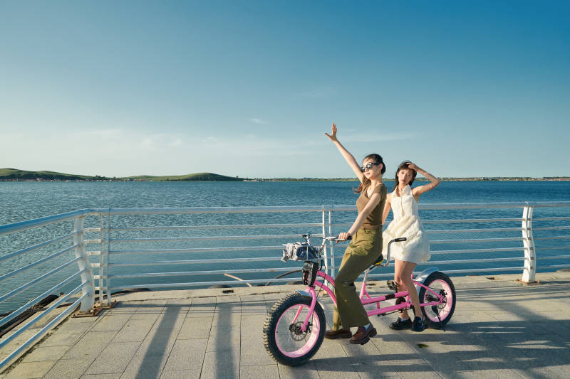 夕阳下湖边码头骑双人脚踏车的闺蜜少女图片