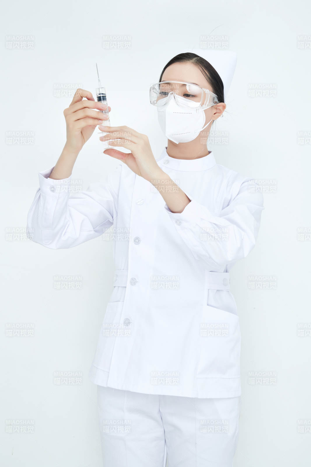 穿护士服戴口罩手执针筒的年轻女护士图片