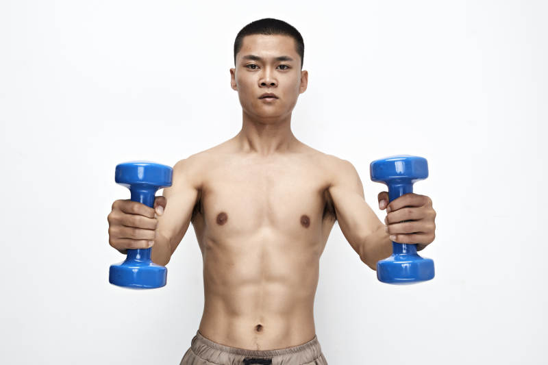 使用哑铃进行健身锻炼的亚洲男性图片