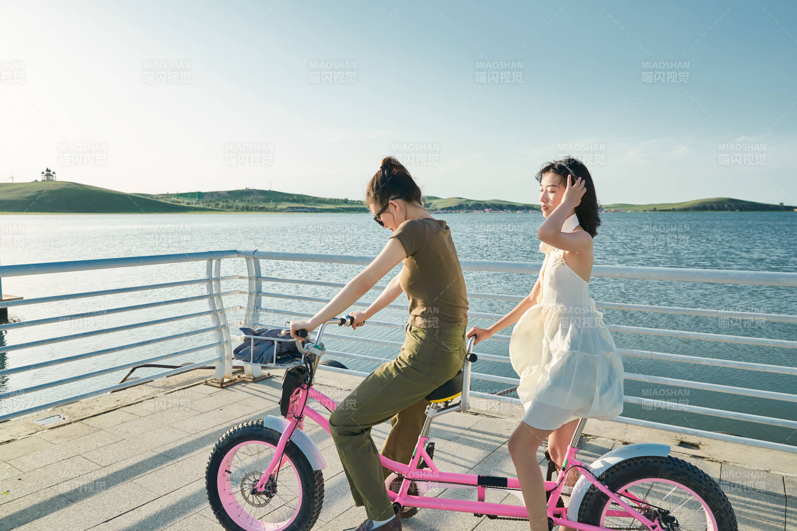 夕阳下湖边码头骑双人脚踏车的闺蜜少女图片