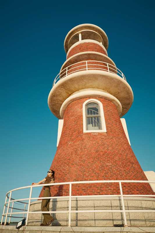 盛夏夕阳晚霞湖边码头灯塔上的少女图片