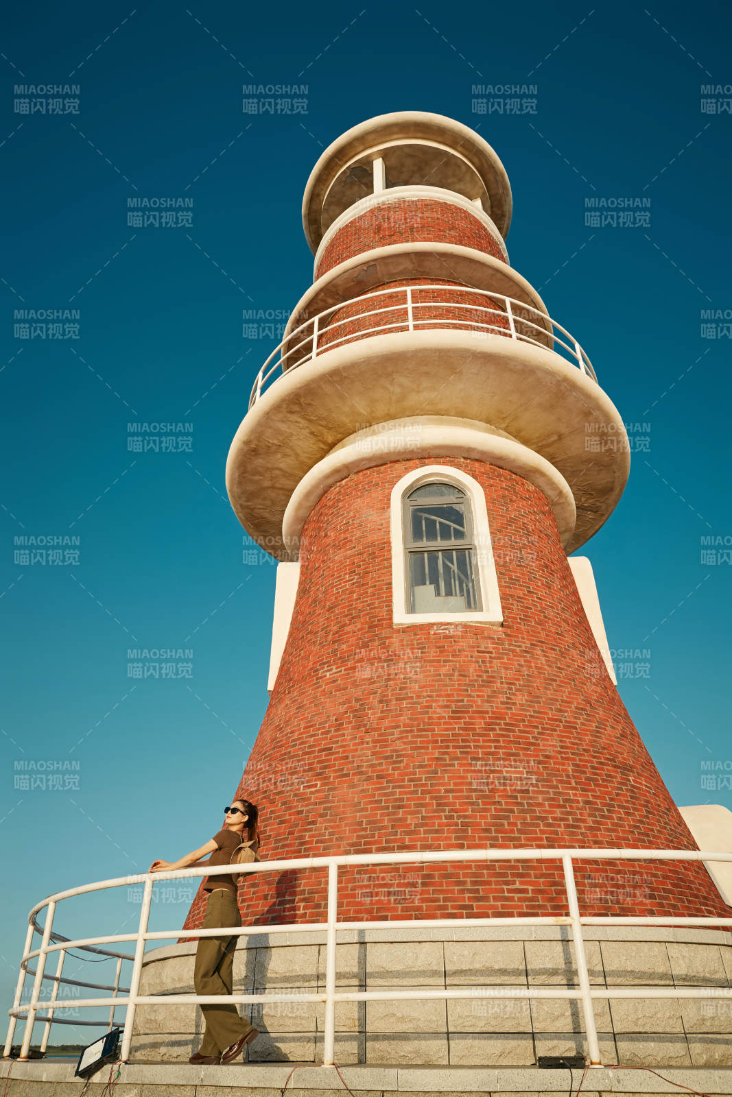盛夏夕阳晚霞湖边码头灯塔上的少女图片