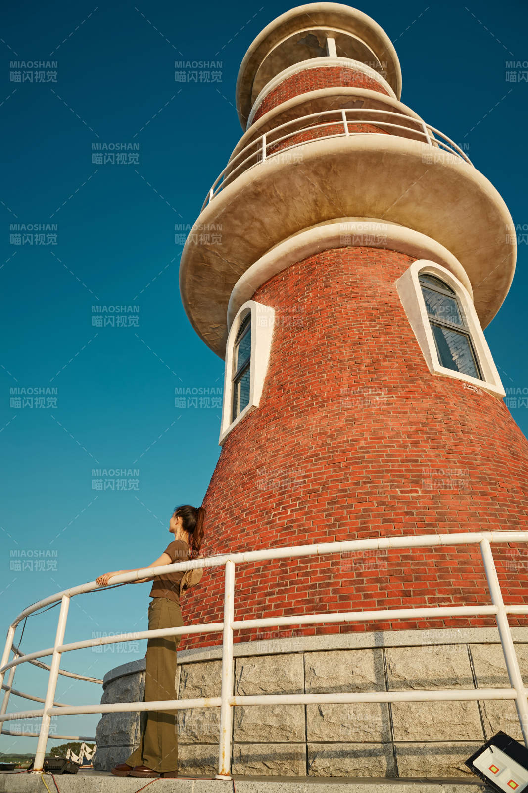 盛夏夕阳晚霞湖边码头灯塔上的少女图片
