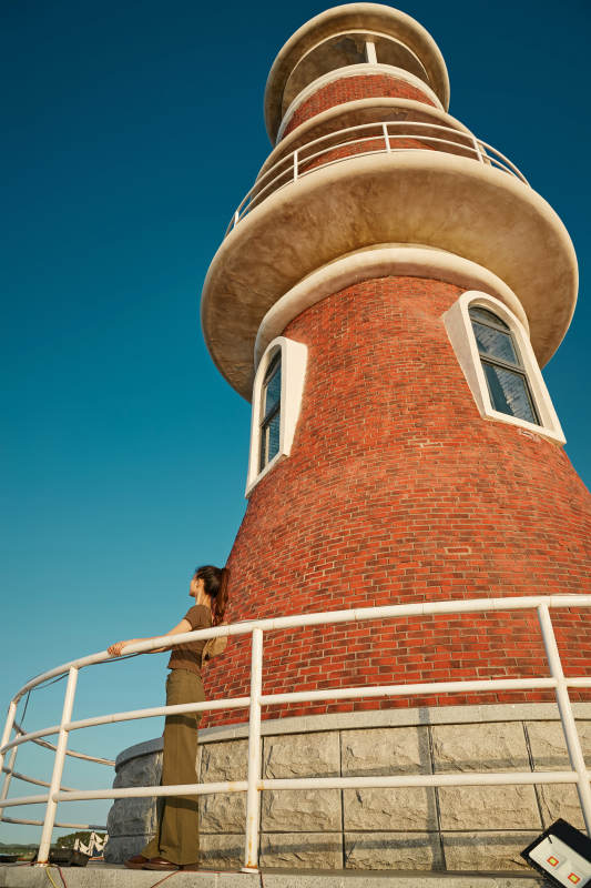 盛夏夕阳晚霞湖边码头灯塔上的少女图片