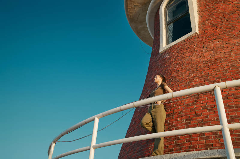 盛夏夕阳晚霞湖边码头灯塔上的少女图片