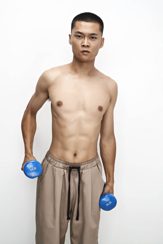 使用哑铃进行健身锻炼的亚洲男性图片