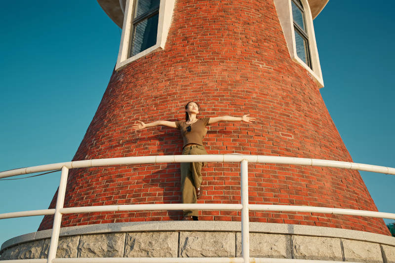 盛夏夕阳晚霞湖边码头灯塔上的少女图片