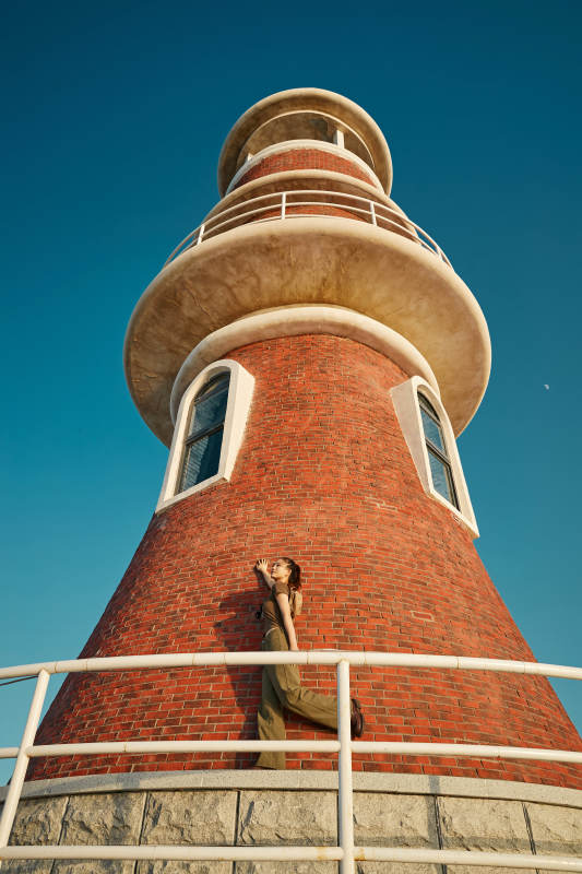 盛夏夕阳晚霞湖边码头灯塔上的少女图片