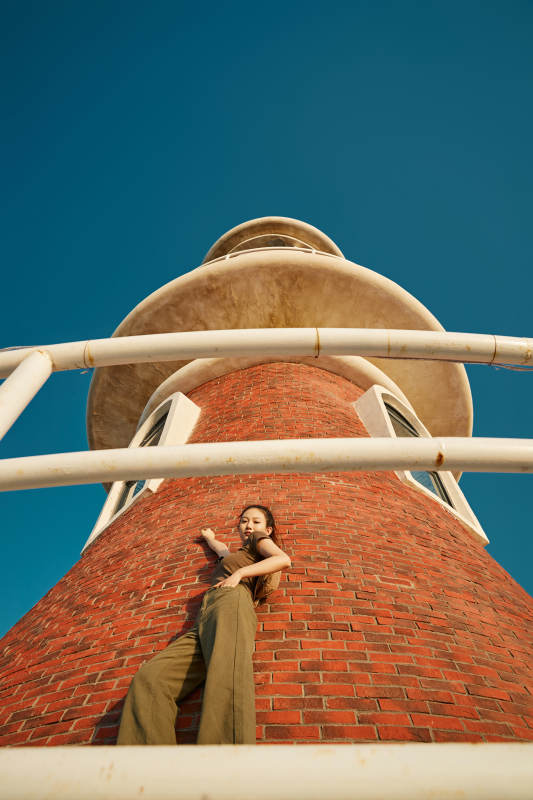 盛夏夕阳晚霞湖边码头灯塔上的少女图片
