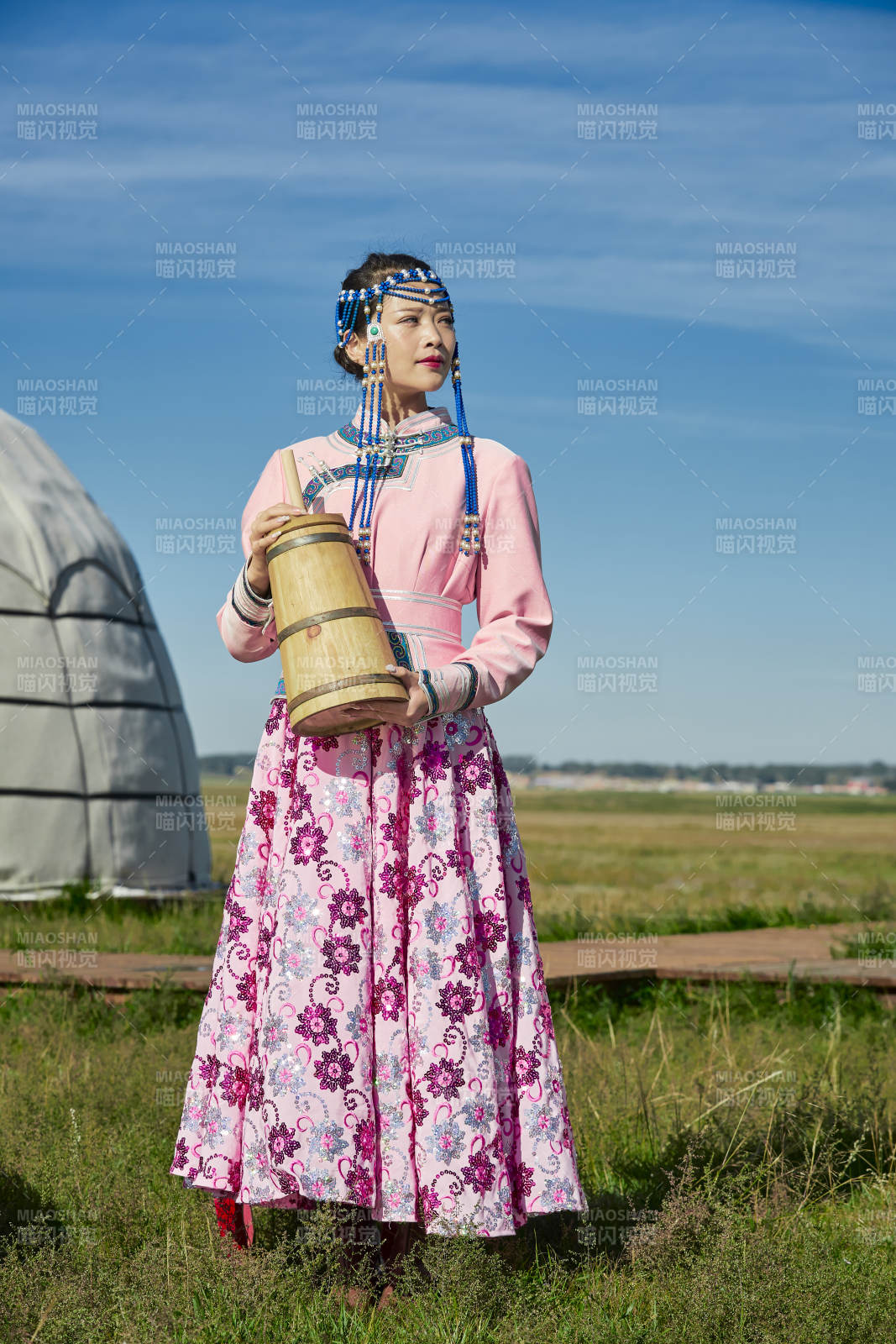 蒙古包前穿蒙古族饰怀抱奶茶桶的蒙族少女图片
