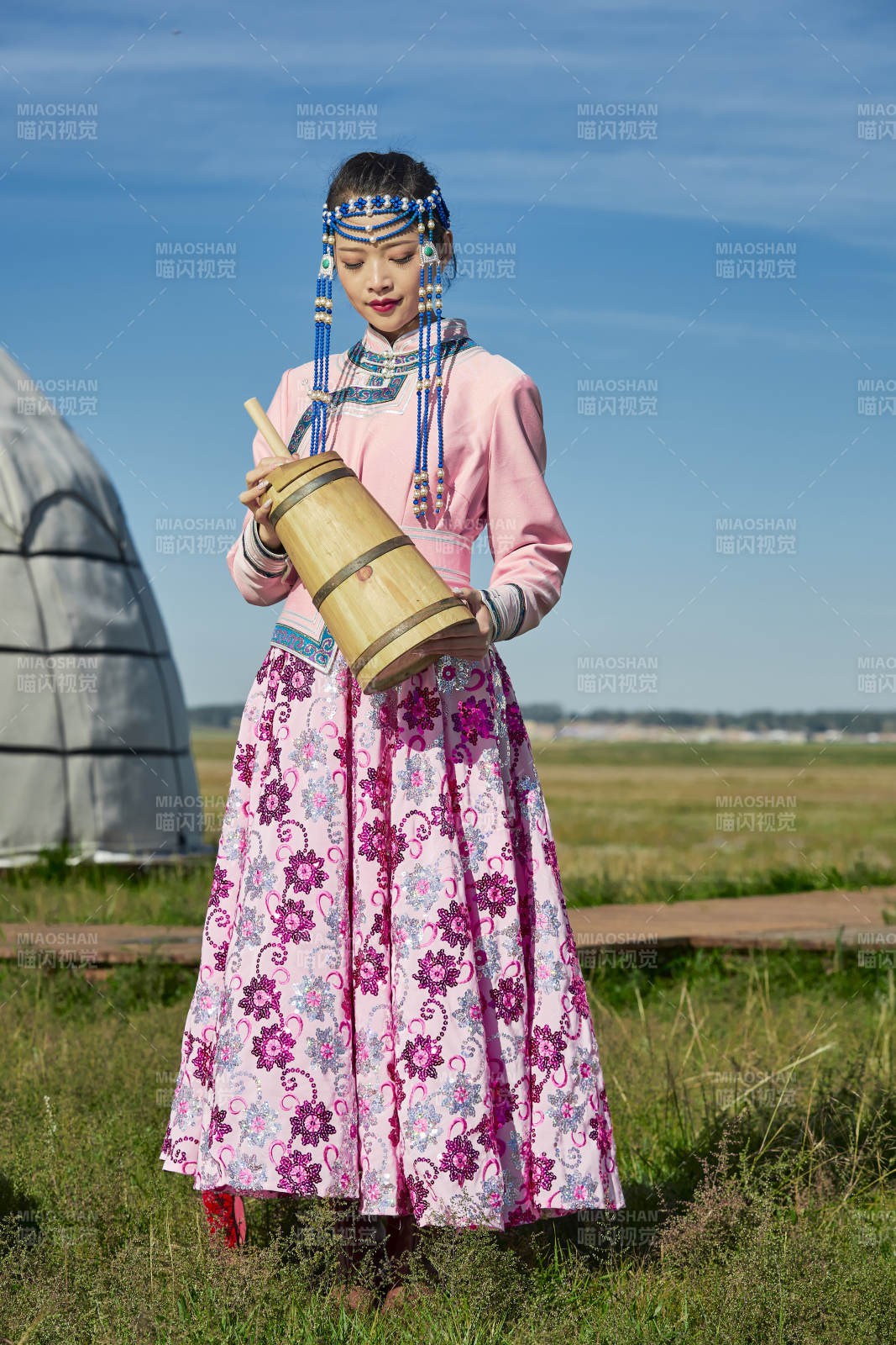 蒙古包前穿蒙古族饰怀抱奶茶桶的蒙族少女图片