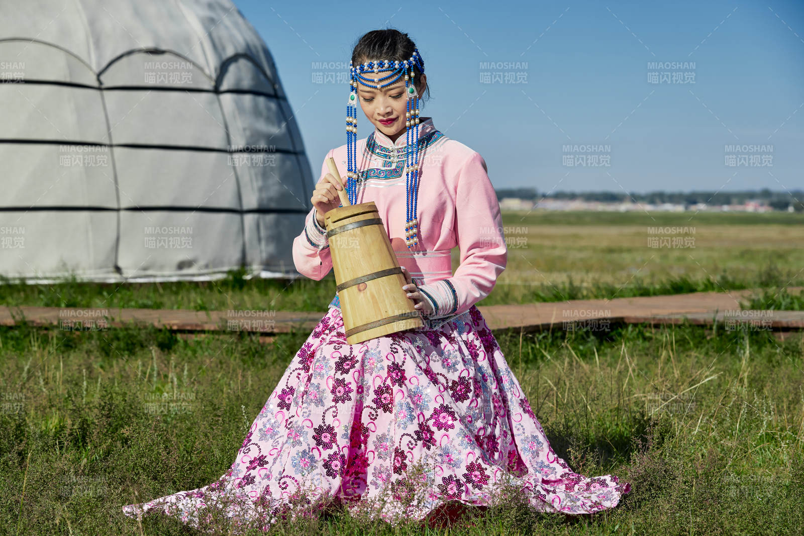 蒙古包前穿蒙古族饰怀抱奶茶桶的蒙族少女图片