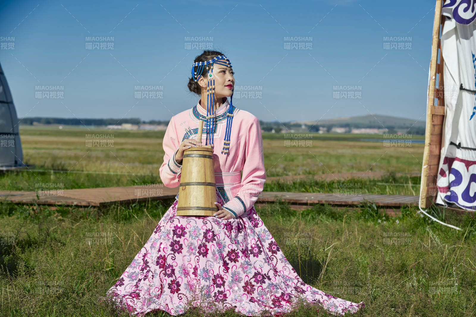 蒙古包前穿蒙古族饰怀抱奶茶桶的蒙族少女图片