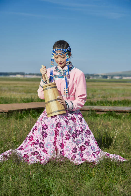 蒙古包前穿蒙古族饰怀抱奶茶桶的蒙族少女图片