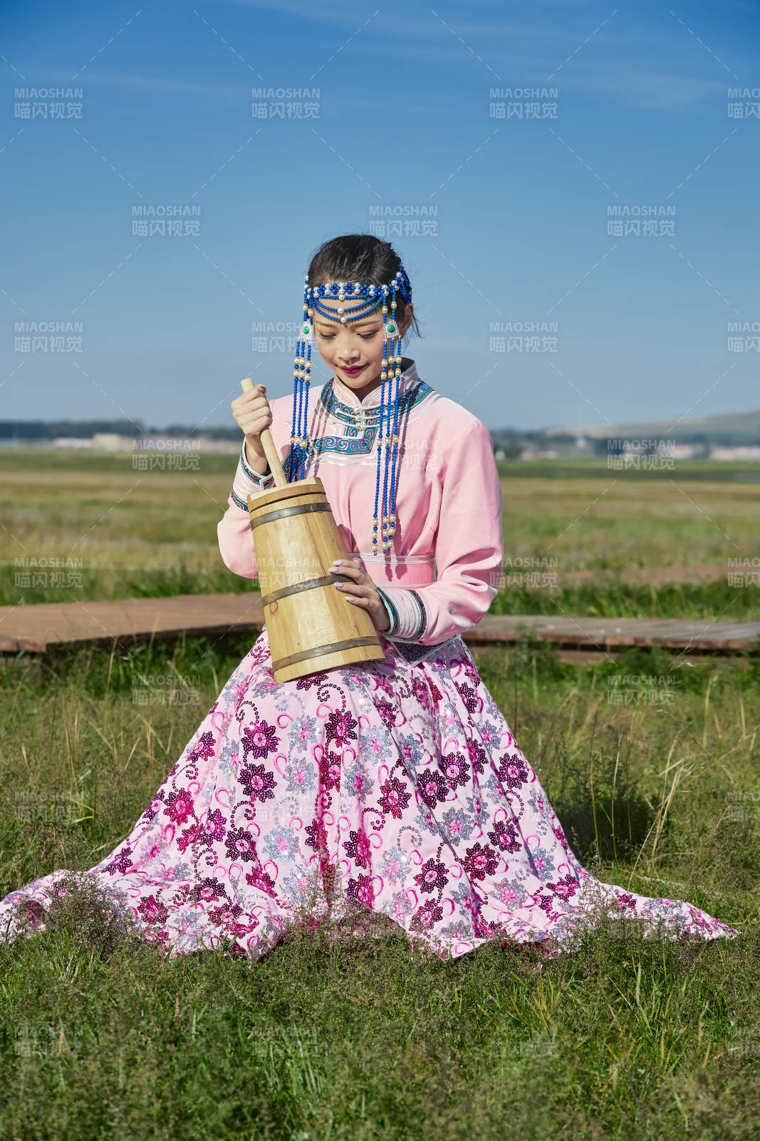 蒙古包前穿蒙古族饰怀抱奶茶桶的蒙族少女图片
